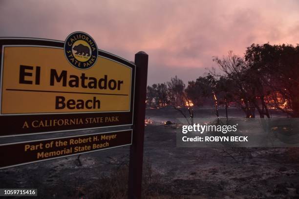 Trees burn at the entrance to El Matador Beach during the Woolsey Fire on November 9, 2018 in Malibu, California. - About 75,000 homes have been...