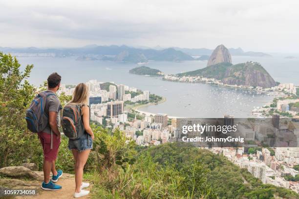 erhöhte aufnahme des paares betrachten der wahrzeichen zuckerhut - rio stock-fotos und bilder