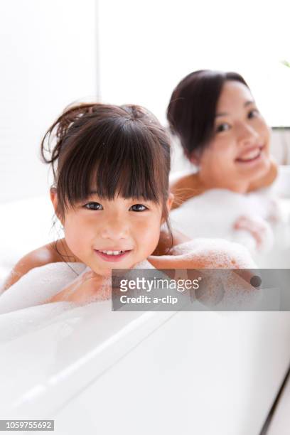mother and daughter bathing in a bubble bath - woman bath bubbles stock pictures, royalty-free photos & images
