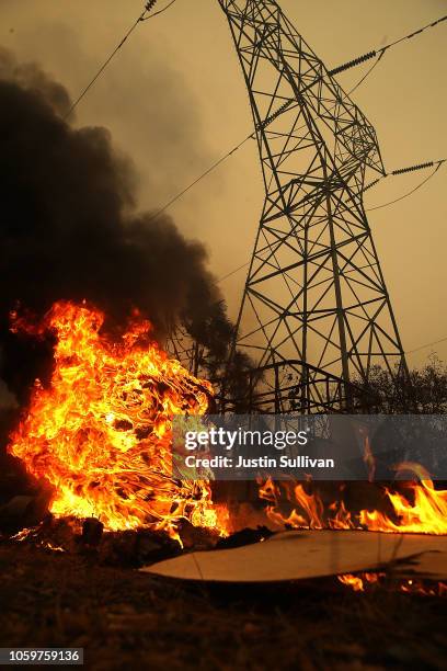 Smoke rises next to a power line tower after the Camp Fire moved through the area on November 9, 2018 in Big Bend, California. Fueled by high winds...