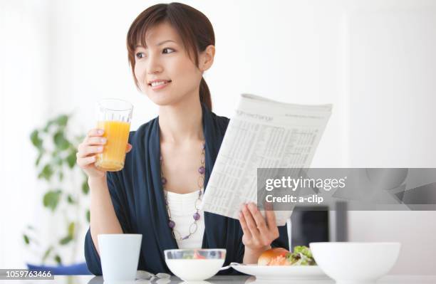 a woman with a glass and a newspaper - businessperson breakfast stock-fotos und bilder