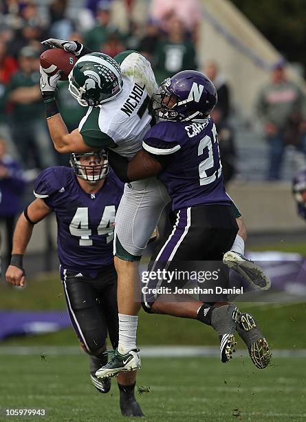 Keith Nichol of the Michigan State Spartans catches a pass as Jared Carpenter of the Northwestern Wildcats makes the hit in the 4th quarter at Ryan...