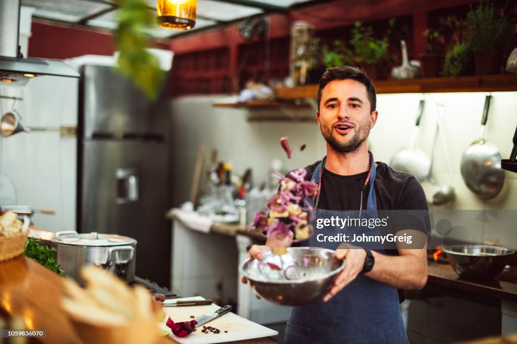 Action portrait of male chef tossing ingredients in bowl