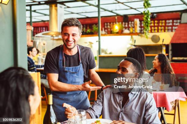 chef mâle riant et discutant avec la main sur l’épaule du client masculin - satisfaction client photos et images de collection