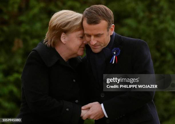 French President Emmanuel Macron and German Chancellor Angela Merkel hug after unveiling a plaque in a French-German ceremony in the clearing of...