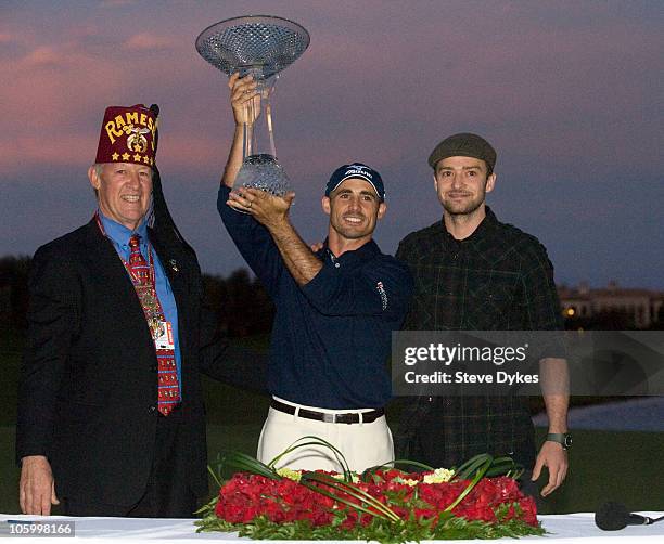 Shriner George Mitchell, golfer Jonathan Byrd and Justin Timberlake pose with the trophy after Byrd hit a hole-in-one to win the tournament at the...