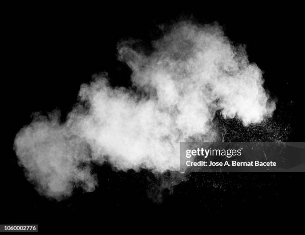 explosion by an impact of a cloud of particles of powder of color white on a black background. - smoke photos et images de collection