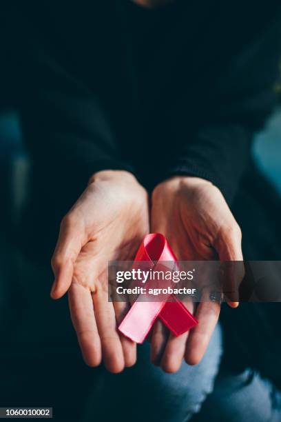 mains de femme donnant de ruban de satin rose - sensibilisation au cancer du sein photos et images de collection