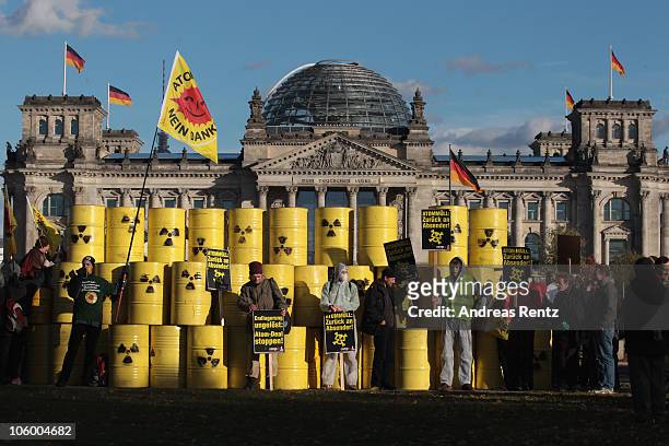 Anti-nuclear protestors stand in front of symbolic nuclear waste barrels as they hold up banners that reads 'Nuclear waste - Return to sender!' near...