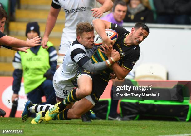 Alex Mitchell of Northampton Saints is tackled by Ian Madigan of Bristol Bears as he scores a try during the Premiership Rugby Cup match between...