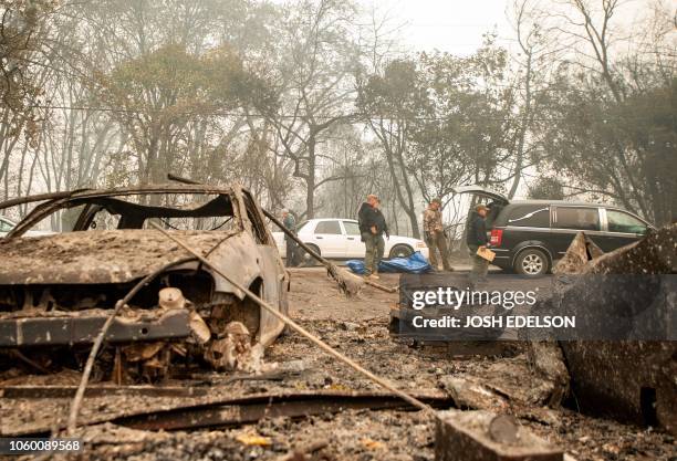 Yuba and Butte County Sheriff officers load a body into a hearse after carrying it away from a burned residence in Paradise, California, on November...