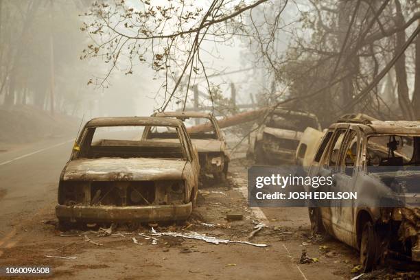 Burnt out vehicles are seen on the side of the road in Paradise, California after the Camp fire tore through the area on November 10, 2018....