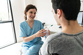 Friendly therapist talking to unrecognizable male patient of a breathing exercise with the spirometer