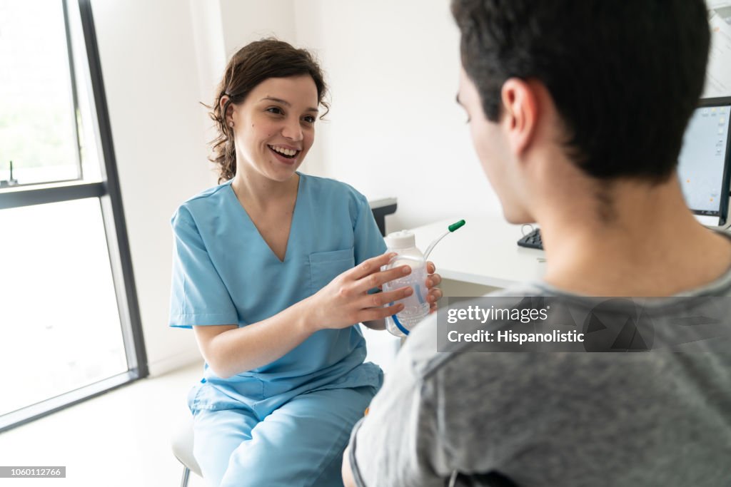 Friendly therapist talking to unrecognizable male patient of a breathing exercise with the spirometer