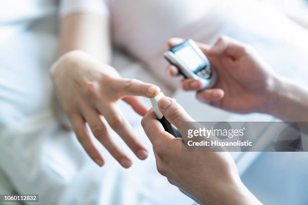 close up van verpleegkundige knijpen patiënten vinger te meten met een glucometer suiker - diabetic stockfoto's en -beelden