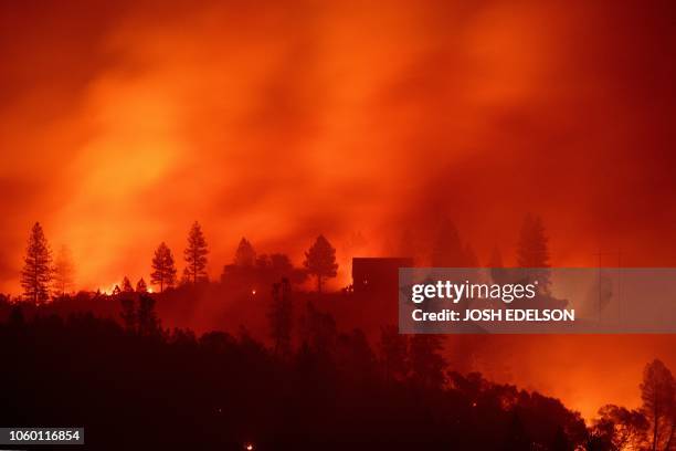 Flames from the Camp fire burn near a home atop a ridge near Big Bend, California, on November 10, 2018. The death toll from the most destructive...