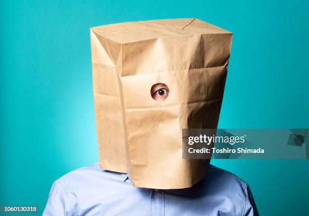 a man pull a paper bag with hole over his head - peephole stock-fotos und bilder