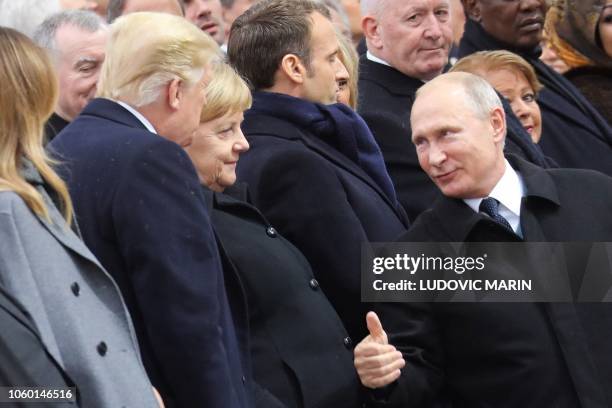 Russian President Vladimir Putin , talks with German Chancellor Angela Merkel and US President Donald Trump as they attend a ceremony at the Arc de...