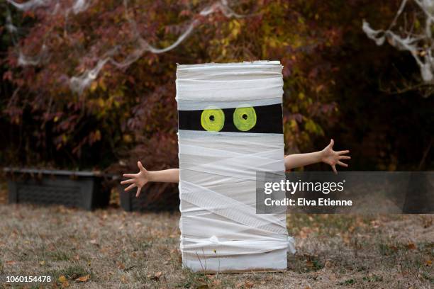 child's hands sticking out from behind halloween cardboard box mummy - mummy stockfoto's en -beelden