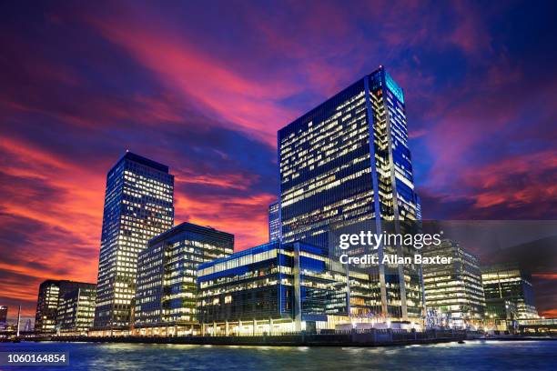 view of canary wharf illuminated at london at sunset - ftse stock-fotos und bilder