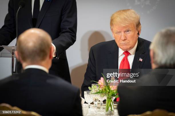 In this handout photo provided by the German Government Press Office , US President Donald Trump sits opposite Russian President Vladimir Putin...