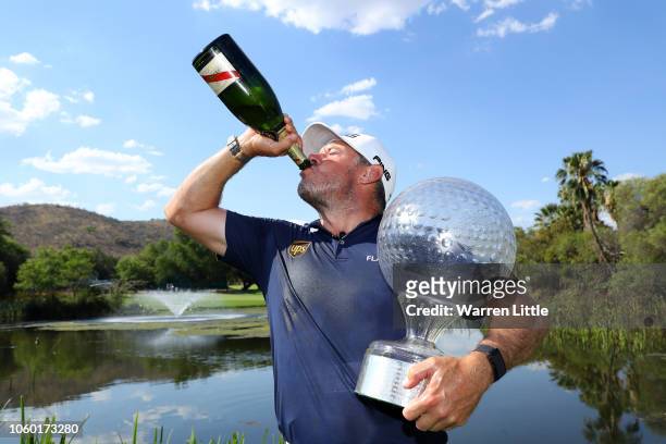 Lee Westwood of England poses with the trophy and drinks champagne after he wins the Nedbank Golf Challenge at Gary Player CC on November 11, 2018 in...