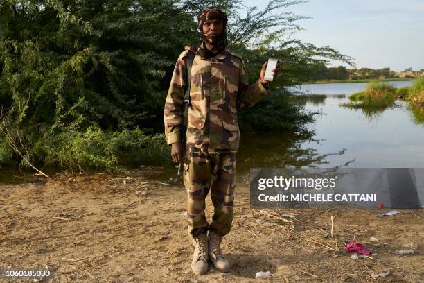 Chadian soldier Ali Adam Agar poses with a smartphone in front of Lake Chad on November 7, 2018. Ali uses his smartphone to listen the Quran's verses...