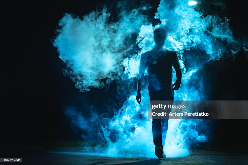The man walking in the blue smoke on the dark background