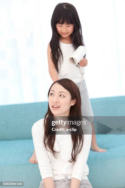 a girl who dries her mother's hair - hair clip fotografías e imágenes de stock