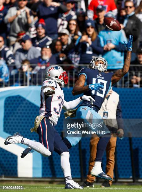 Tajae Sharpe of the Tennessee Titans reaches for a pass from Marcus Mariota while defended by Jason McCourty of the New England Patriots during the...