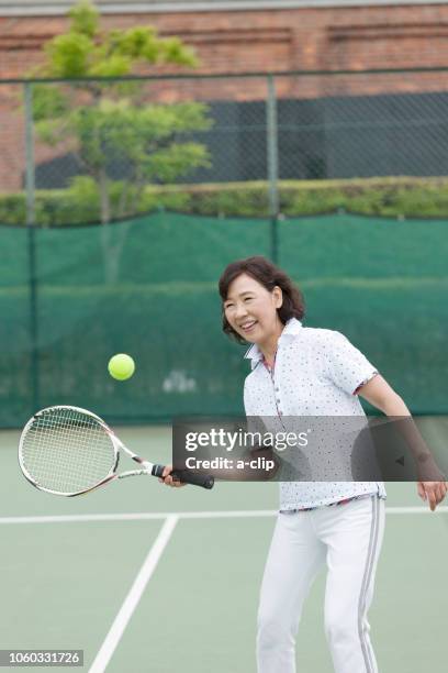 mature woman playing tennis - japanese tennis stock-fotos und bilder