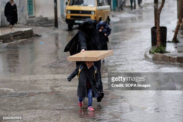 Mother seen protecting her child from rain in the centre of Gaza City.