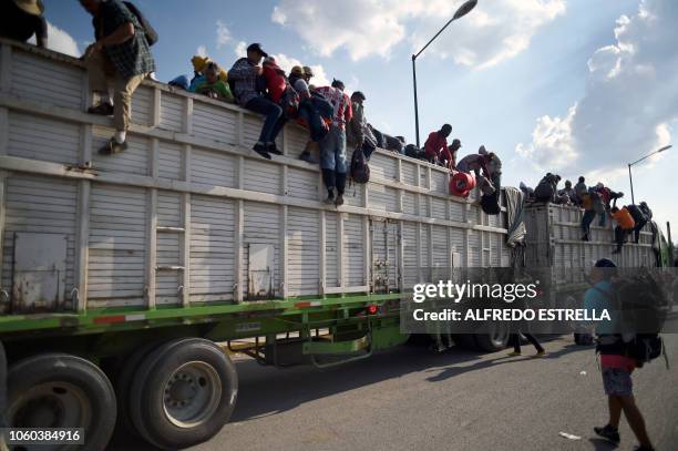 Central American migrants -mostly Hondurans- taking part in a caravan heading to the US, descend from a truck, on arrival at a temporary shelter in...