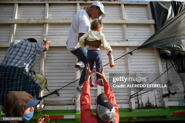 Central American migrants -mostly Hondurans- taking part in a caravan heading to the US, descend from a truck, on arrival at a temporary shelter in...