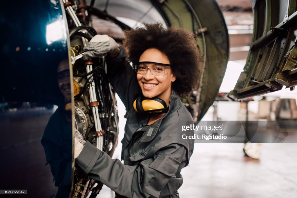 Happy woman repairing aircraft