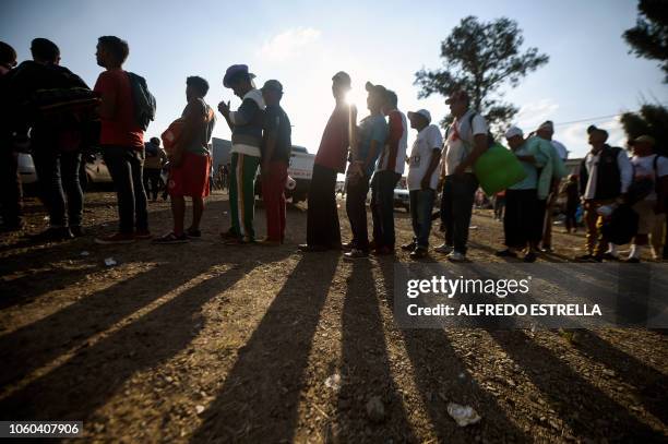 Central American migrants, taking part in a caravan heading to the US, queue to receive a meal at a temporary shelter in Irapuato, Guanajuato state,...