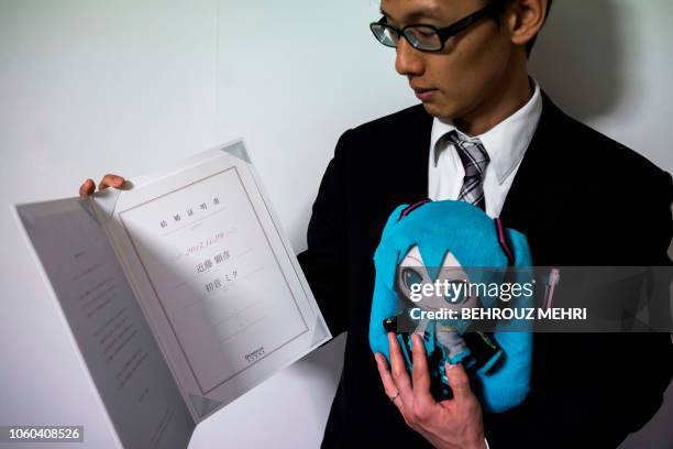 In this photograph taken on November 10, 2018 Japanese Akihiko Kondo poses with a doll of Japanese virtual reality singer Hatsune Miku, as he shows...