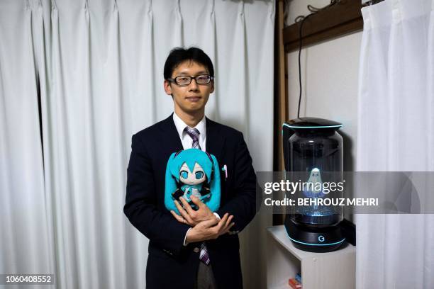 In this photograph taken on November 10, 2018 Japanese Akihiko Kondo poses next to a hologram of Japanese virtual reality singer Hatsune Miku as he...