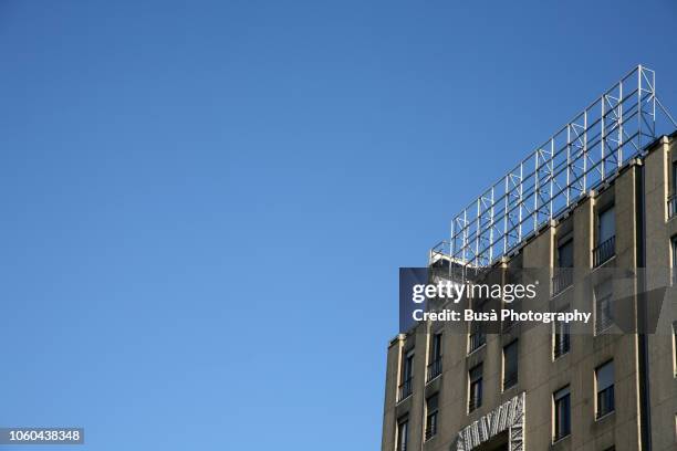 top of elegant art deco building with scaffolding of large billboard sign. milan, italy - 足場 ストックフォトと画像