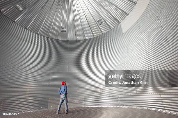 farmer stands in a empty silo/drying bin.  - silo fotografías e imágenes de stock