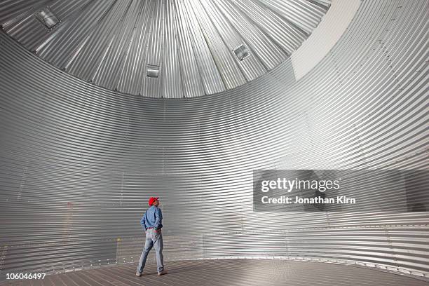 farmer stands in a empty silo/drying bin.  - silos stock pictures, royalty-free photos & images