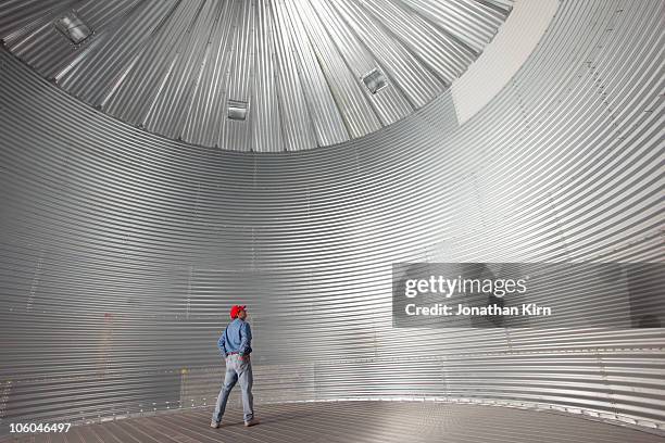 farmer stands in a empty silo/drying bin.  - 筒倉 個照片及圖片檔