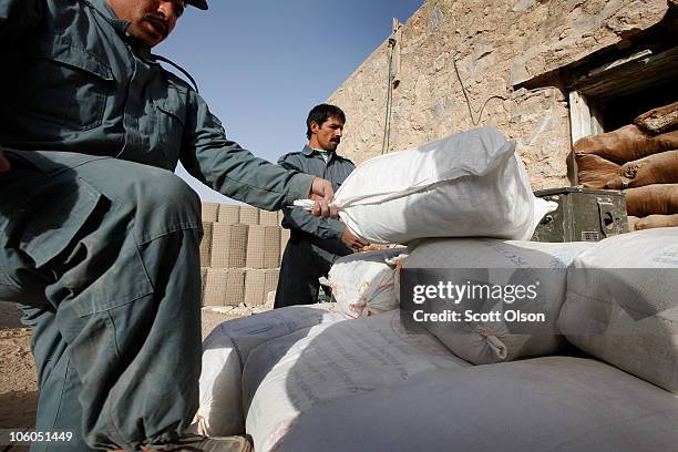 Afghanistan National Police officers load wheat seed onto a truck at Forward Operating Base Zeebrugge on October 25, 2010 in Kajaki, Afghanistan. The...