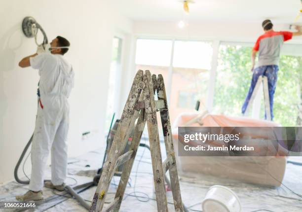 manual workers brushing wall after plaster and before final painting - pintor fotografías e imágenes de stock