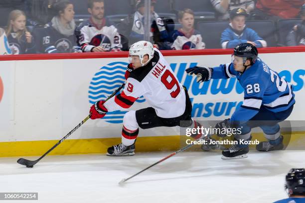 Taylor Hall of the New Jersey Devils plays the puck along the boards as Jack Roslovic of the Winnipeg Jets gives chase during third period action at...