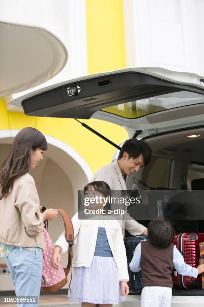車から荷物をおろす4人家族 - lowering ストックフォトと画像
