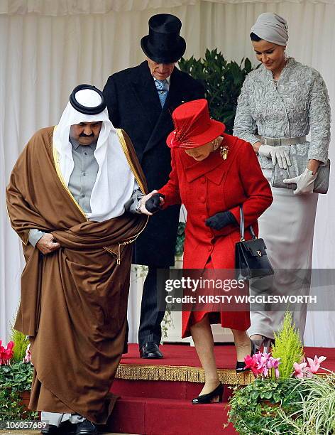 Britain's Queen Elizabeth II , takes the hand of Qatar's emir, Sheikh Hamad bin Khalifa al-Thani , as they walk down a set of steps with Prince...