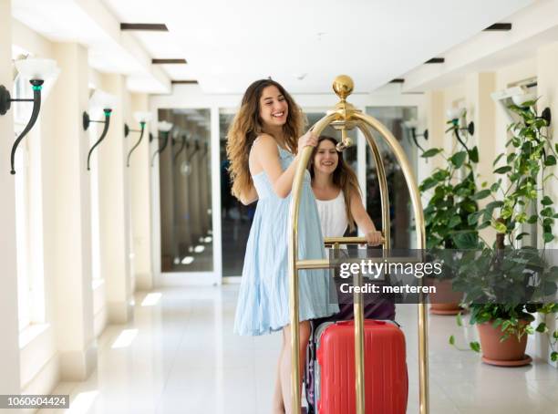 two beautiful women using baggage cart - luggage trolley stock pictures, royalty-free photos & images