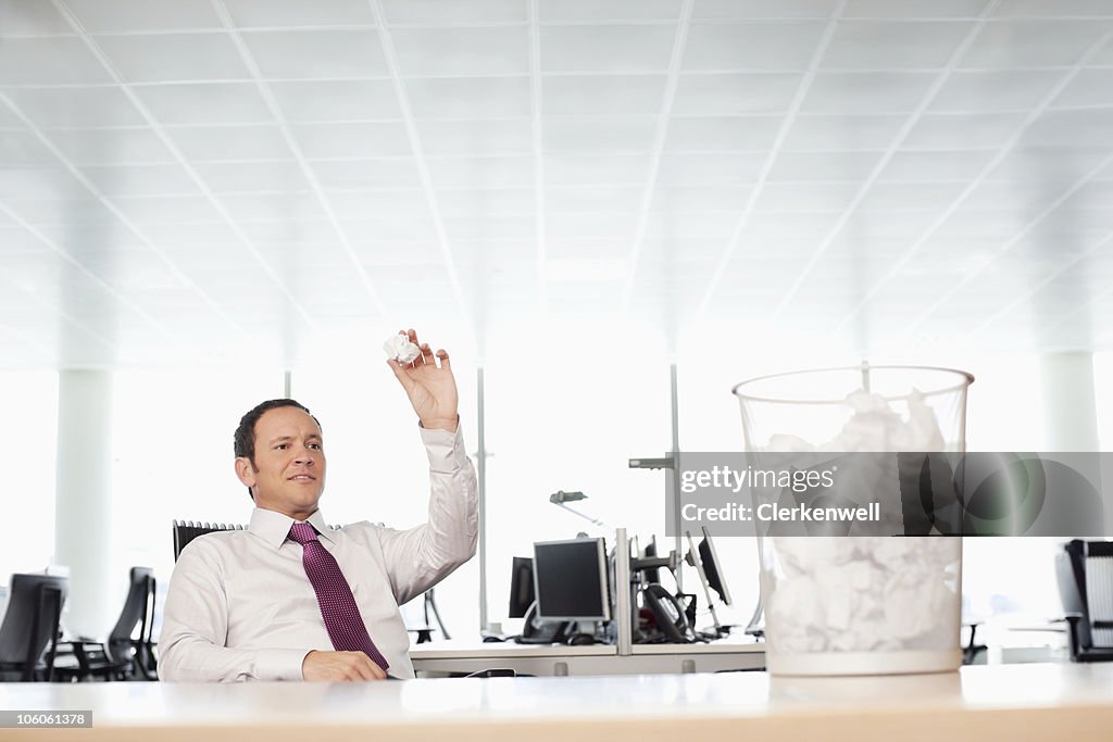 Businessman tossing crumpled paper at waste bin