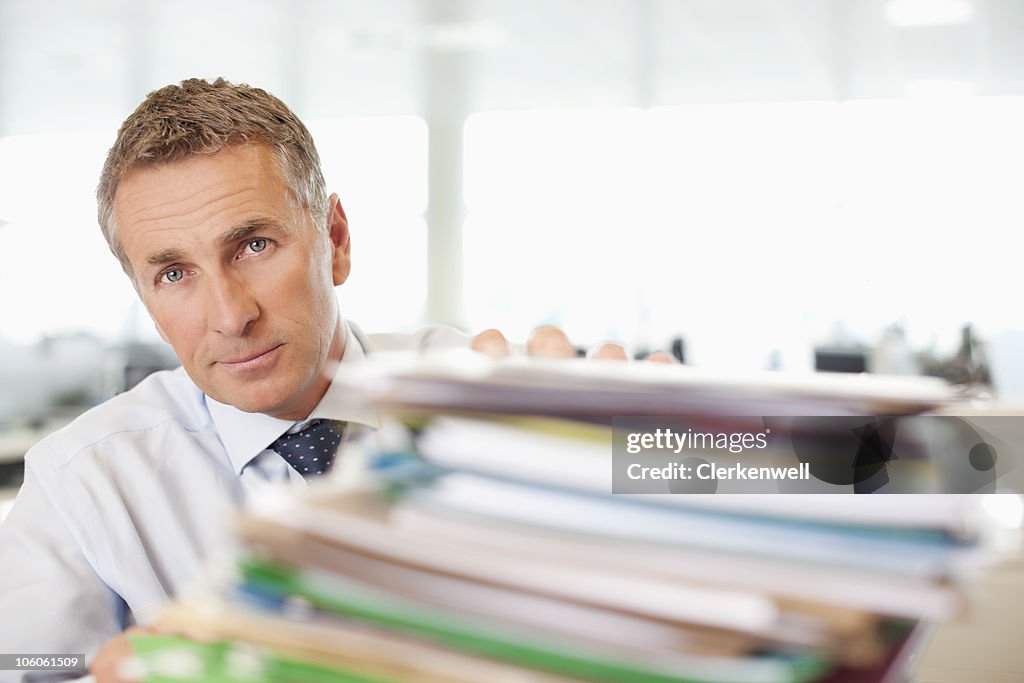 Close-up of a mature businessman with heap of papers